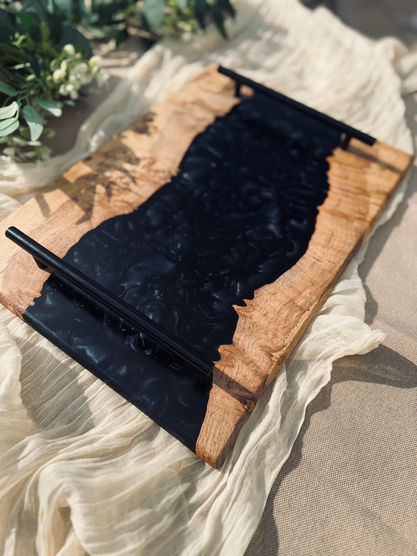 Oak burr and black onyx epoxy serving tray on a garden table under a beige table cloth