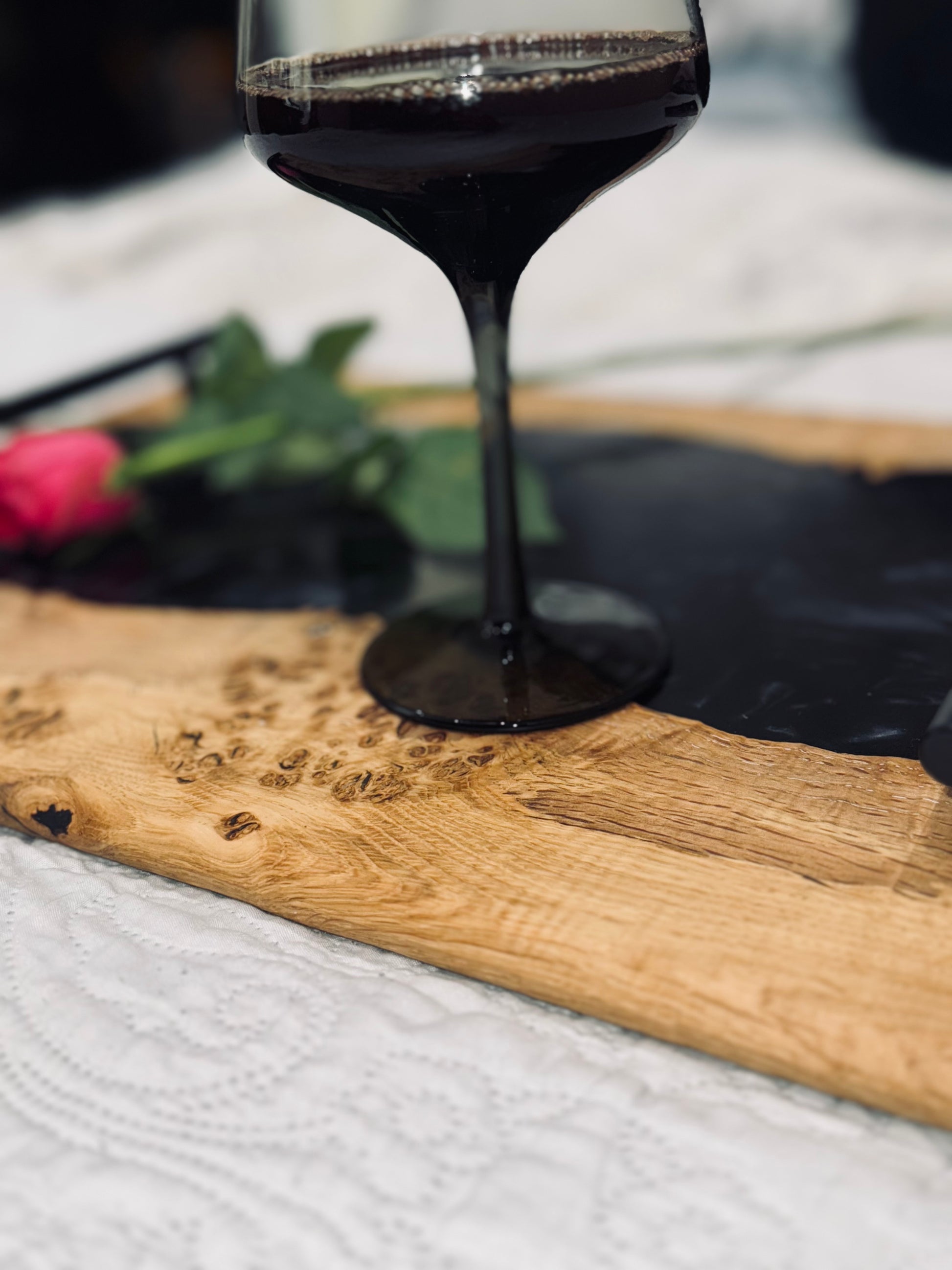 Oak burr and black onyx epoxy serving tray staged on a bed, close up